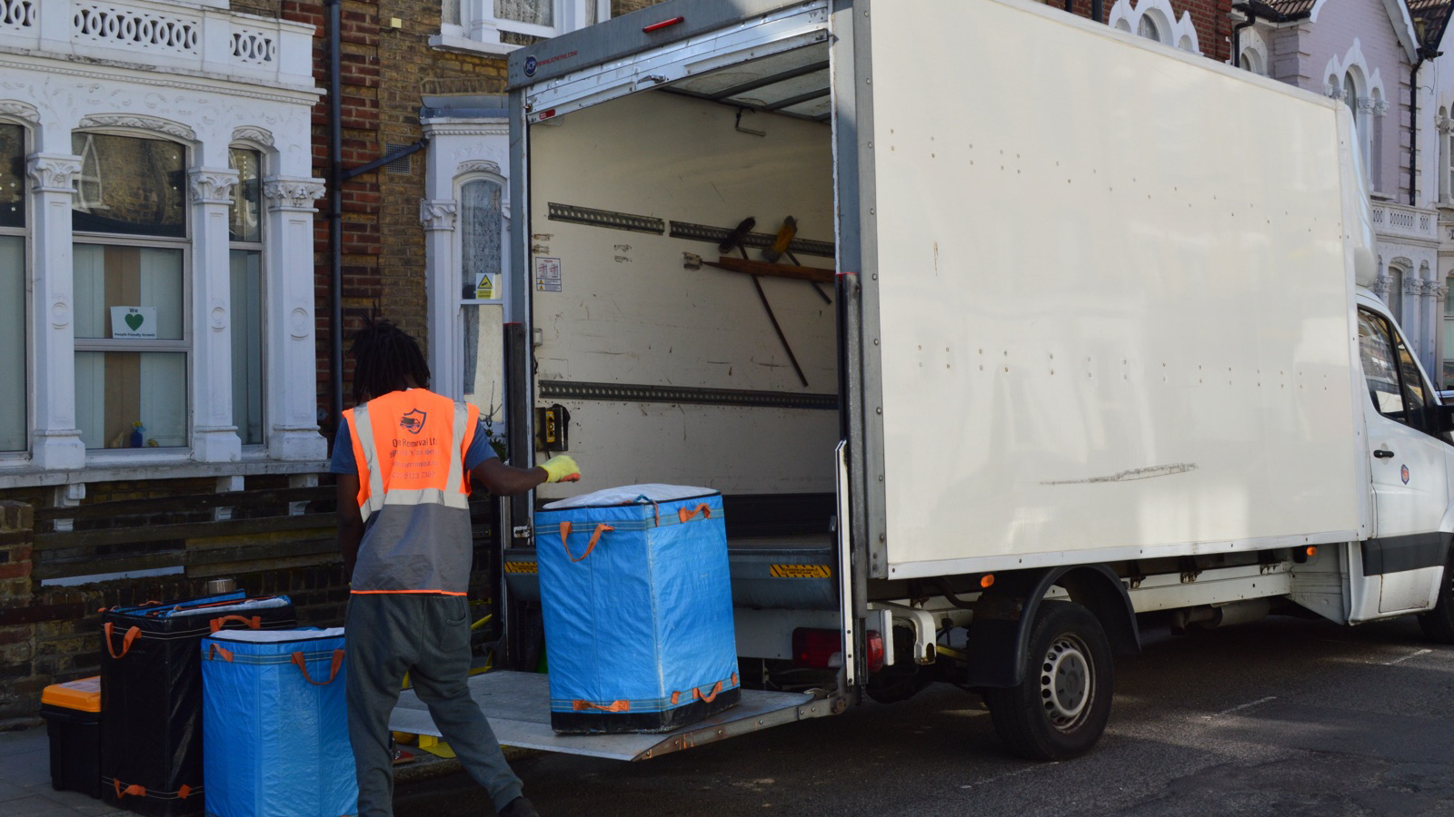Men With Van mover loading a Luton removal van outside a London residential property