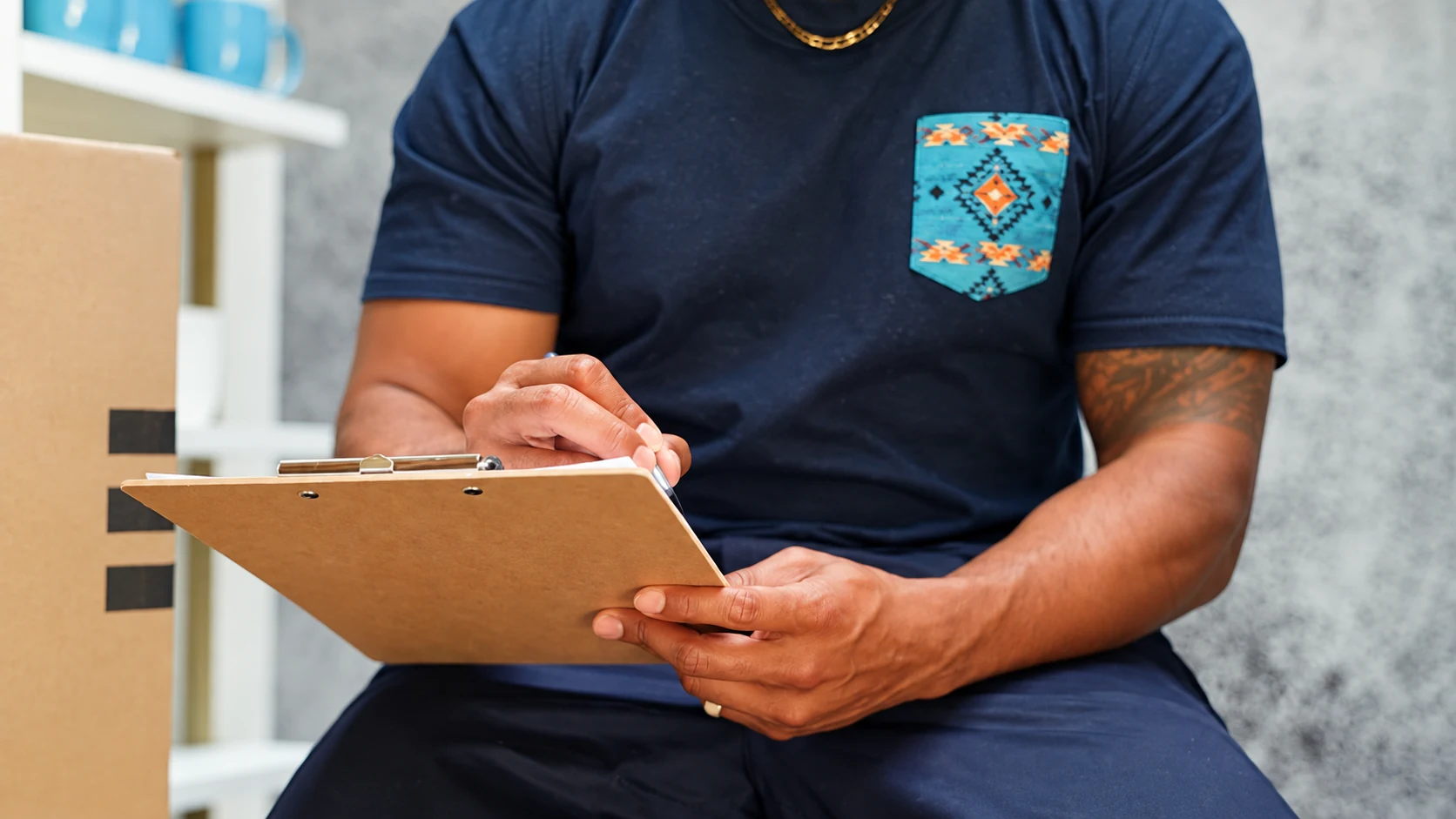 A person holding a clipboard beside packed boxes while planning a move