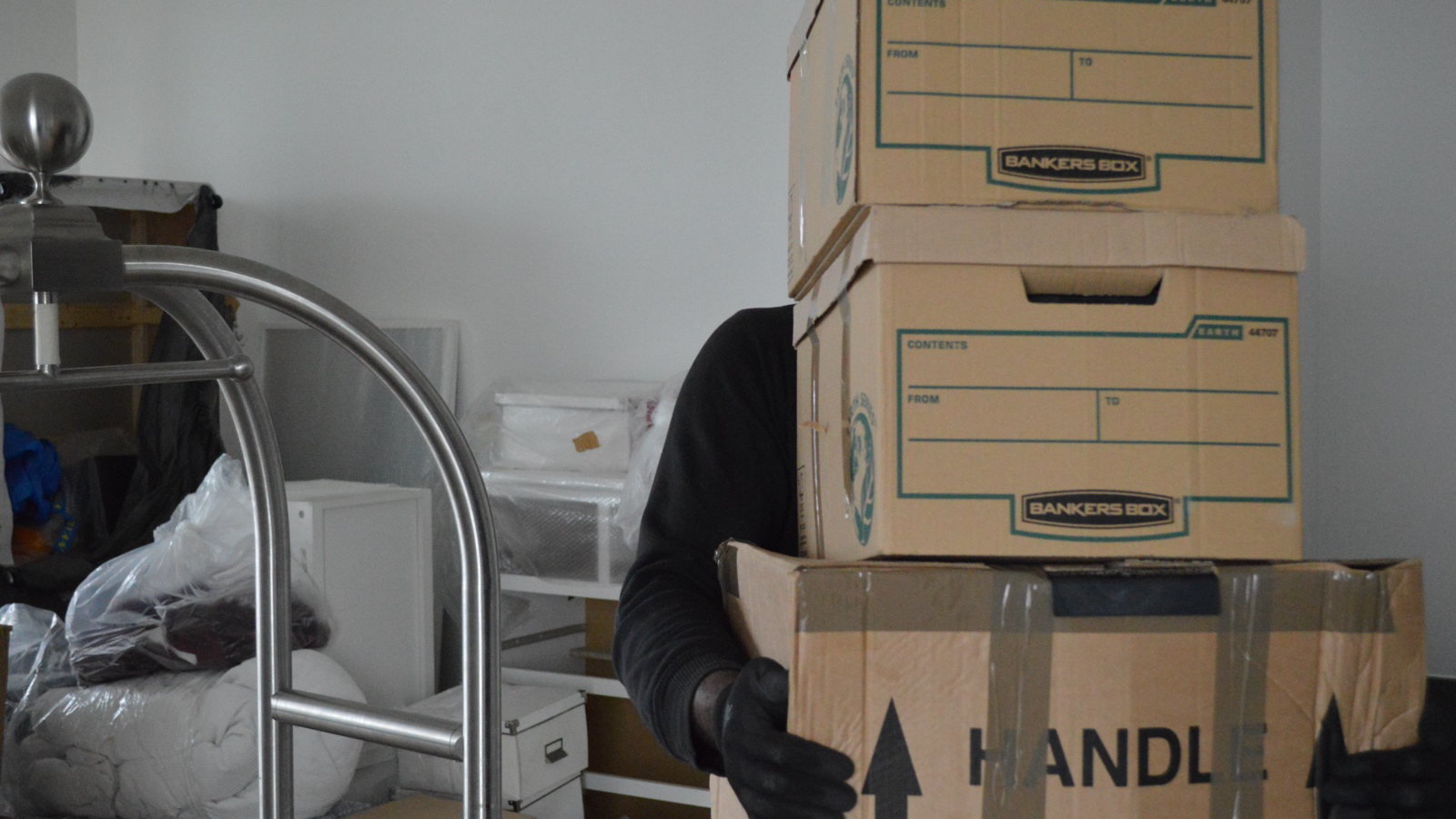 Mover carrying sealed removal boxes inside a property during an operational Men With Van job