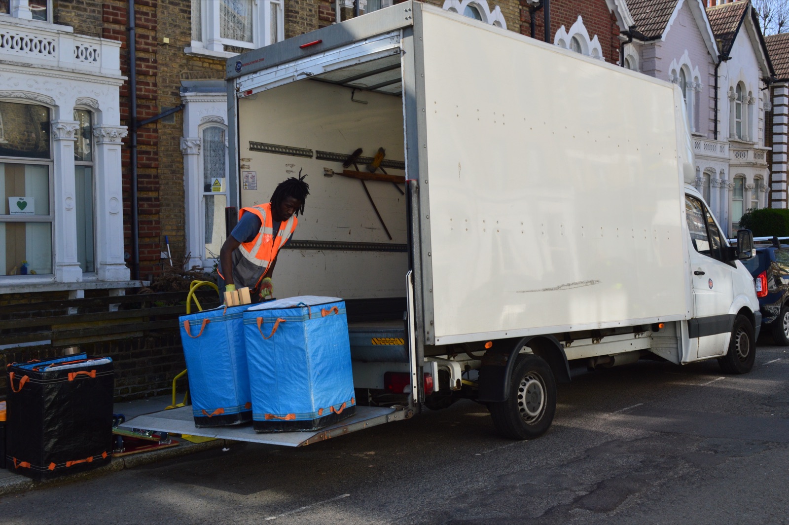 Blue moving bags loaded by Luton van tail lift