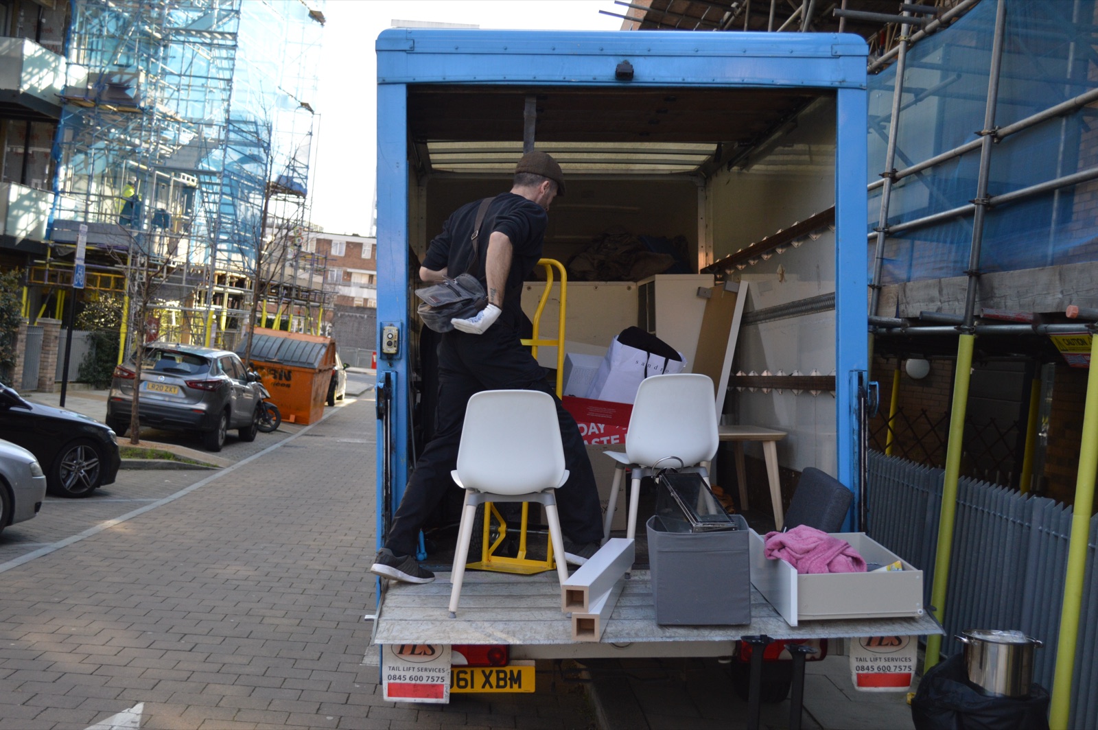 Blue removal van open at the tail lift with furniture ready for loading