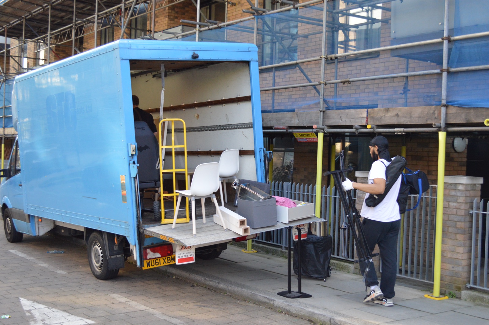 Removal van tail lift with furniture and movers loading items carefully